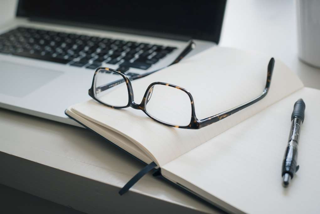 Gros plan sur des lunettes de vue, un agenda et un ordinateur portable